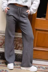 Pantalón tejido de punto color beige, de corte holgado y perneras anchas, con cintura elástica y cordón ajustable.