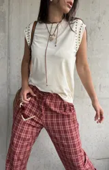 Remera sin mangas de color manteca, con detalle de tachas metálicas doradas en los hombros.