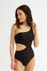 Malla entera negra con diseño asimétrico de un solo hombro y aberturas cut-out en la cintura. Presenta un tejido texturizado de rayas horizontales.