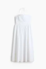 Vestido midi de algodón color blanco, con escote halter y breteles para atar en la nuca. Presenta detalles de encaje en el escote y la cintura, y falda fruncida con leve vuelo.