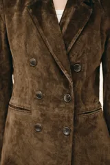 Blazer de ante color marrón, con cuello solapa, hombreras, manga larga y cierre frontal cruzado con botones. Cuenta con bolsillos delanteros de doble vivo.