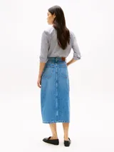 Falda midi de denim rígido celeste, corte recto de talle alto, con cinco bolsillos, abertura frontal y cierre de cremallera con botón.