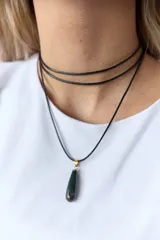 Gargantilla con tres tiras de cuero negro y dije de piedra natural verde oscuro con engarce dorado.