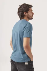 Remera de manga corta color azul grisáceo, con cuello redondo y un pequeño texto bordado en negro en el pecho.