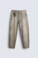Pantalón de corte relajado confeccionado en tejido de algodón con efecto lavado. Presenta diseño de cinco bolsillos, cierre frontal con cremallera y botón, y detalles de estampados a contraste en la parte delantera y trasera.