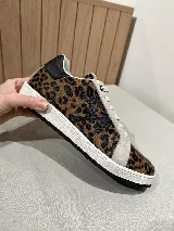 Championes de cuero color blanco con detalle de corona en animal print y talón verde. Cuentan con suela de caucho, lengüeta de gamuza y forro textil, con cierre mediante cordones al tono.