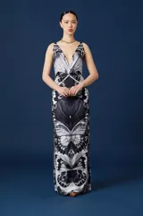 Vestido largo de jersey elastizado con estampado de mariposas en tonos blanco y negro. Presenta un escote en V profundo, breteles finos y un nudo central en el torso que define la silueta, con un corte recto y fluido.