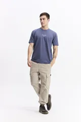 Remera de manga corta color azul apagado con cuello redondo y fit regular. Presenta un pequeño estampado de lettering blanco en el pecho.