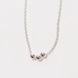 Collar plateado con cadena de eslabones y tres dijes de bolitas plateadas.
