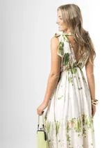 Vestido largo confeccionado en mezcla de tencel y lino, con fondo off white y estampado floral en tonos rosados, rojos y verdes. Cuenta con escote en V pronunciado, breteles anchos ajustables con lazos en los hombros, corte bajo el busto y falda amplia con volados escalonados.