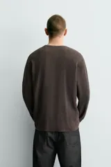 Jersey relaxed fit de punto acanalado color marrón oscuro, con cuello redondo tipo panadera y cierre frontal de tres botones. Tiene manga larga y efecto lavado.