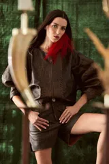 Campera de cuero con silueta oversize y corte levemente corto. Presenta cierre frontal metálico, cuello a la base y mangas amplias con detalles trenzados y recortes que aportan textura.