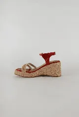 Sandalias de taco chino con plataforma revestida en yute natural. Posee capellada de tiras cruzadas de yute en la parte delantera, puntera cuadrada y tira ajustable de cuero rojo metalizado en el talón.