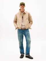 Campera Tommy Hilfiger modelo Ivy, color beige, confeccionada en tejido técnico impermeable y resistente al viento. Cuenta con cuello clásico, cierre frontal de cremallera, bolsillos laterales ribeteados y parche engomado en la manga.