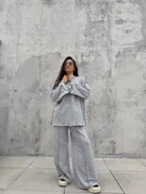 Buzo oversize de color gris, con diseño de costuras expuestas en contraste y terminaciones desflecadas en mangas y ruedo.
