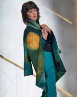 Tapado de lana merino afieltrada con teñido artesanal tie dye en tonos verdes y ocres. Tiene cuello alto, cierre cruzado asimétrico con broches, bolsillos laterales y corte holgado.