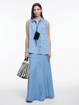 Camisa sin mangas en denim color celeste, confeccionada en 100% lyocell. De corte recto y largo medio, presenta cartera escondida en el frente y un bolsillo plaqué en el pecho. En la espalda, tiene botones decorativos alineados en abertura vertical y pespuntes a contratono.