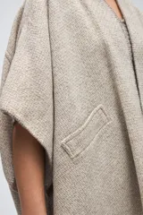 Ruana corta de lana fina sin teñir, con bolsillos laterales y terminaciones tejidas a crochet hechas a mano.