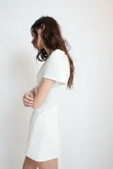 Vestido corto de Zara, color blanco, con escote en pico, mangas cortas abullonadas y detalle de lazo frontal en el mismo tejido. Presenta un corte entallado y cierre de cremallera oculta en la espalda.