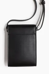 Bolso bandolera chico color negro, de cuero sintético, con correa ajustable y solapa con hebilla metálica decorativa y botón a presión oculto.