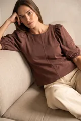 Remera de algodón negro con mangas cortas abullonadas, cuello redondo y costura central frontal.
