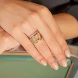 Anillo de diseño entrelazado fabricado en oro de 18k, combinando bandas en oro amarillo y oro blanco con incrustaciones de circonias.