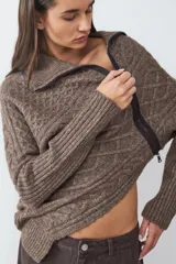 Sweater de punto con diseño de trenzas, cuello polo con cierre frontal asimétrico, manga larga y corte relajado.