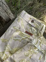 Bombacha de campo de gabardina color beige con estampado botánico en tonos verde oliva, de corte tradicional con trabillas para cinto y botón frontal.