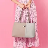 Cartera tipo tote de cuero sintético con diseño combinado en tono gris y blanco, textura granulada, asas largas para el hombro y cierre superior.