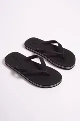 Ojota de hombre marca Mistral, color blanco con detalles de líneas negras en el borde de la suela. Presenta textura rayada en la base y logo de la marca en relieve tanto en la plantilla como en las tiras.