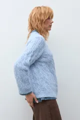 Sweater de punto con diseño de trenzas verticales, color rosa melange, de cuello redondo y manga larga con puños acanalados.