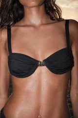 Top de bikini con aros y escote corazón, color negro, con detalle de aplicación metálica combinada en el centro del pecho. Tirantes finos ajustables.
