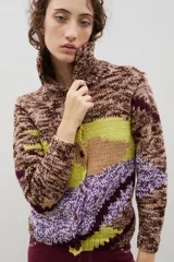 Saco de punto con diseño de bloques de color en técnica intarsia, combinando tonos marrones jaspeados, verde lima y violeta. Presenta cuello redondo, cierre frontal con botones y mangas largas.
