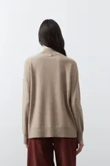 Polera de tejido de punto color gris oscuro, con cuello alto y diseño de rombos en relieve en el frente. Presenta un calce relajado con terminaciones en rib en cuello, puños y ruedo.