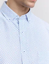 Camisa celeste con pequeños lunares blancos, de manga larga, con cuello abotonado y bolsillo en el pecho.