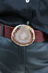 Cinto de cuero azul con hebilla circular de piedra ágata con borde dorado.