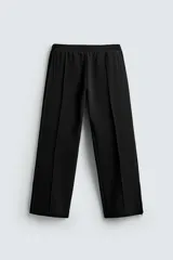 Pantalón relaxed fit color negro, confeccionado en tejido fluido con viscosa. Cuenta con cintura elástica ajustable con cordón interior, bolsillos laterales y bolsillos traseros de vivo. Las perneras tienen costura frontal y el bajo es ajustable con cremalleras laterales.