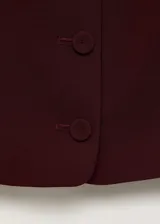 Chaleco bordó de cuello redondo abierto, tirantes anchos, cierre frontal de botones y diseño recto de estilo sastrero.