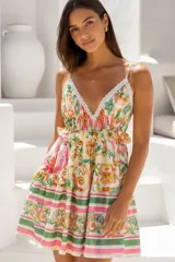 Vestido corto de tirantes finos, con escote en V ribeteado de encaje blanco, estampado multicolor estilo barroco con tonos verdes, rosados y amarillos, y diseño acampanado con volados.