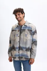 Sobrecamisa de hombre con estampado tribal en tonos gris claro, azul y marrón, de manga larga, cuello clásico, bolsillos frontales con solapa y cierre de botones.