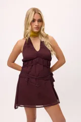 Vestido corto color borgoña, con escote halter, tiras finas y detalle de lazos en la cintura.