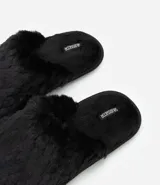 Pantufla cerrada de mujer con textura de peluche suave en color negro, diseñada para brindar comodidad en el hogar.