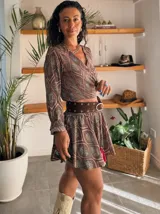 Conjunto de dos piezas compuesto por un top de mangas largas con escote cruzado y una falda corta acampanada, ambos con estampado estilo paisley en tonos marrones y turquesas.