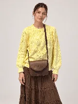 Sweater de hilo tejido color amarillo, con cuello redondo, calce cómodo y mangas amplias con puños acanalados. Presenta detalles de trenzas y flecos en el frente.