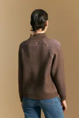 Polera de tejido acanalado en color marrón con detalles de líneas en tono lila, cuello alto y mangas largas con diseño raglán.