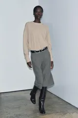 Bermuda larga gris confeccionada en hilatura con viscosa, de tiro medio y cintura con trabillas. Presenta bolsillos laterales ocultos en costura, detalle de raya plancha y cierre frontal con cremallera, botón y ganchos metálicos.