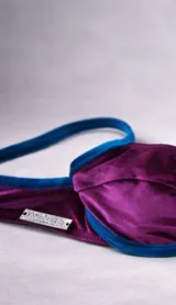 Top de bikini negro con aro y estribo metálico dorado en el centro.