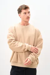 Buzo color beige de corte holgado, con cuello redondo y mangas largas.