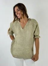 Blusa de lino color beige claro, con escote en V con volado, mangas cortas abullonadas con elástico en el puño y corte holgado.