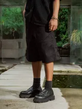 Bermuda negra de gabardina, corte ancho y largo, con bolsillos laterales.